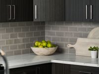 Elegant kitchen corner with soft close dark wood cabinets, modern backsplash, and quartz countertops.