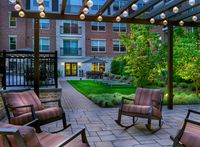 Experience our charming outdoor courtyard with modern seating, lush greenery, and ambient lighting, perfect for relaxation.