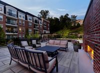Chic outdoor lounge area with elegant seating and scenic views, surrounded by lush greenery and modern architecture.