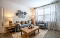 Modern, cozy living spaces with stylish décor, luxury flooring, and warm wood accents for a welcoming feel. Bright and inviting living room with modern decor, showcasing a cozy gray sofa and armchair, wooden coffee table, and elegant wall art.