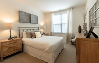 Spacious bedroom in a modern apartment featuring luxury carpeting, ample natural light, and a sleek, contemporary design for a comfortable and stylish retreat. Charming bedroom with chic decor, showcasing modern art, stylish wooden furniture, and warm lighting for a cozy atmosphere.