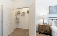 Spacious bedrooms featuring luxury carpeting, ample natural light, and spacious closets, creating a comfortable and stylish retreat. Inviting bedroom with a cozy walk-in closet, elegant lamp on a stylish wooden nightstand, and modern decor enhancing the serene ambiance.
