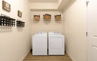 The convenience of an in-unit washer and dryer for a comfortable and stylish living experience. Modern laundry room with efficient washer and dryer, wall-mounted storage baskets, and stylish decor.