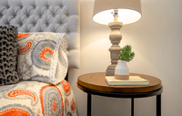 Spacious bedroom in a modern apartment featuring luxury carpeting, ample natural light, and a sleek, contemporary design for a comfortable and stylish retreat. Chic bedside setup with a tufted headboard, vibrant patterned bedding, stylish lamp, and elegant side table featuring a succulent decor.
