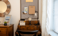 Spacious bedroom in a modern apartment featuring luxury carpeting, ample natural light, and a sleek, contemporary design for a comfortable and stylish retreat. Charming study nook featuring a rustic wooden desk with a globe, wall-mounted planner, and cozy decor.
