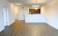 Modern, spacious living areas with luxury flooring and warm wood accents for a welcoming feel. Inviting open-plan apartment with modern kitchen, sleek stainless steel appliances, and elegant wood flooring.