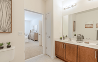 Spacious bedroom in a modern apartment featuring luxury carpeting, ample natural light, and a sleek, contemporary design for a comfortable and stylish retreat. Luxurious bathroom with double sinks and elegant decor next to a stylish, well-lit bedroom.