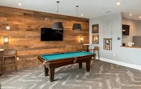 Our clubhouse offers a fun and vibrant space with a billiards table and a variety of games, perfect for relaxing and socializing with friends and neighbors. Chic recreation room with a pool table, rustic wood paneling, modern lighting, and stylish decor.