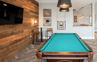 Our clubhouse offers a fun and vibrant space with a billiards table and a variety of games, perfect for relaxing and socializing with friends and neighbors. Modern recreation room in an upscale apartment with a stylish pool table, rustic wooden accent wall, and elegant lighting, offering a perfect blend of comfort and entertainment.