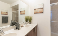 Spacious bedroom in a modern apartment featuring luxury carpeting, ample natural light, and a sleek, contemporary design for a comfortable and stylish retreat. Elegant bathroom featuring a dual-sink vanity with sleek fixtures, modern decor, and a spacious glass-enclosed shower.