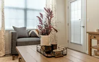 Modern, cozy living spaces with stylish décor, luxury flooring, and warm wood accents for a welcoming feel. Charming living room corner featuring a cozy gray sofa, stylish throw pillow, and a rustic coffee table adorned with a decorative plant arrangement.