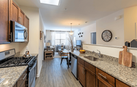 Gourmet-inspired kitchen featuring designer cabinetry, sleek granite countertops, and high-end stainless steel appliances. Inviting open-concept kitchen and living area with elegant granite countertops and modern appliances leading into a sunlit, cozy living space.