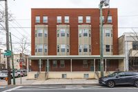 Charming multi-story brick building with bay windows on a vibrant city street corner, offering potential urban living spaces.