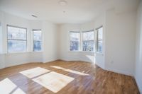 Bright and inviting room with large bay windows and gleaming hardwood floors, perfect for enjoying natural sunlight.
