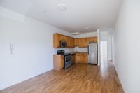 Chic open kitchen with modern stainless steel appliances, elegant wooden cabinetry, and sleek hardwood flooring.