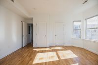 Bright and airy room with polished hardwood floors, ample sunlight through large windows, and modern door fixtures.