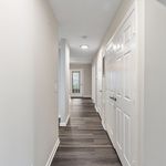 Bright and inviting hallway with sleek wooden flooring, contemporary doors, and modern lighting, leading to a glass-paneled exit.