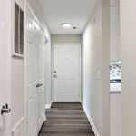 Inviting apartment entryway with sleek hardwood floors, freshly painted walls, and elegant white doors leading to modern interiors.