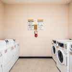 Modern laundry room with multiple washers and dryers, featuring a bright and clean design for convenient living.