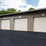 Modern and secure garage units with sleek white doors, providing ample storage space in a landscaped community setting.