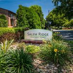 Welcoming entrance of Salem Ridge Apartment Homes, surrounded by lush greenery and vibrant flowers.