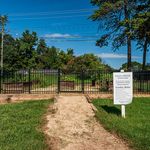 Welcoming entrance to a community garden with lush greenery and a charming pathway, perfect for relaxing and enjoying nature.