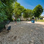 Inviting outdoor play area featuring lush trees, exercise elements, and a cozy bench, perfect for relaxation and recreation.