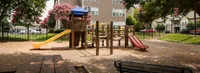 Charming playground with colorful slides and climbing structures surrounded by lush greenery, ideal for family living.