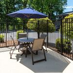 Charming outdoor patio with elegant seating set and vibrant blue umbrella, perfect for relaxing and entertaining.