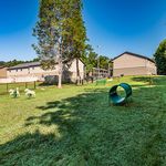 Charming apartment exterior view showcasing lush green outdoor space with play area, inviting benches, and scenic surroundings for relaxation.