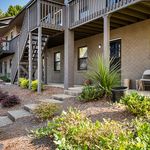 Charming apartment exterior with garden landscaping and elevated balcony, ideal for outdoor relaxation.