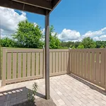 Charming outdoor patio with modern fencing, surrounded by lush greenery and a serene blue sky.