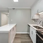 Modern kitchen with sleek white cabinetry, stainless steel appliances, and elegant tile backsplash in a cozy apartment setting.