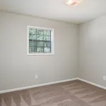 Bright and inviting bedroom with plush carpeting and a window overlooking lush greenery.