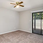 Bright, airy bedroom with plush carpet, ceiling fan, and large glass doors opening to a serene patio.