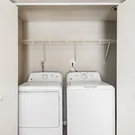 Modern laundry nook featuring sleek washer and dryer with convenient overhead shelving.