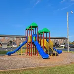 Bright and inviting playground with colorful slides and climbing structures, set in a vibrant community backdrop under a clear blue sky.