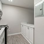 Modern kitchen featuring sleek white cabinetry, stainless steel appliances, and elegant laminate flooring.