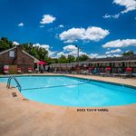 Inviting outdoor pool area with vibrant red lounge chairs under a clear blue sky, perfect for relaxation and enjoying sunny days.