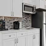 Modern kitchen with sleek stainless steel appliances, elegant white cabinetry, and stylish tile backsplash.