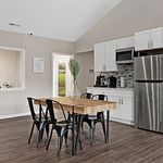 Modern kitchen and dining area with sleek stainless steel appliances, chic wooden dining table, and elegant cabinetry, perfect for stylish living.