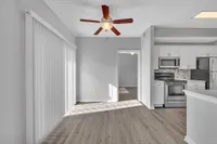 Bright modern apartment featuring sleek gray flooring, stainless steel kitchen appliances, and large sliding glass doors for abundant natural light.