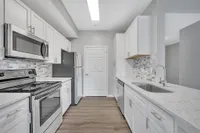 Sleek modern kitchen with white cabinetry, stainless steel appliances, and elegant marble countertops.