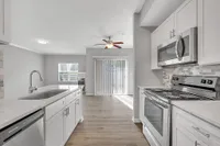 Modern kitchen with sleek appliances, elegant white cabinetry, and sunlit open-plan dining area.