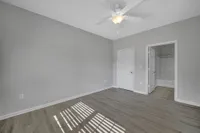 Bright and spacious bedroom with modern wood flooring and ceiling fan, featuring an en-suite bathroom for ultimate convenience.