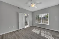 Bright and airy bedroom with elegant gray walls, a large window letting in natural light, and stylish wood flooring.