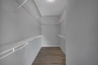 Spacious walk-in closet with elegant wire shelving and sleek hardwood floors, perfect for organized living.