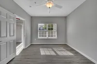 Bright, spacious bedroom with modern ceiling fan, large window, and elegant flooring in a stylish apartment.