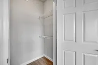 Bright and spacious walk-in closet with sleek shelving and elegant wooden flooring, perfect for organized storage.