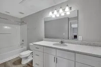 Modern bathroom with elegant white vanity, marble countertop, and bright overhead lighting, creating a sleek and inviting atmosphere.